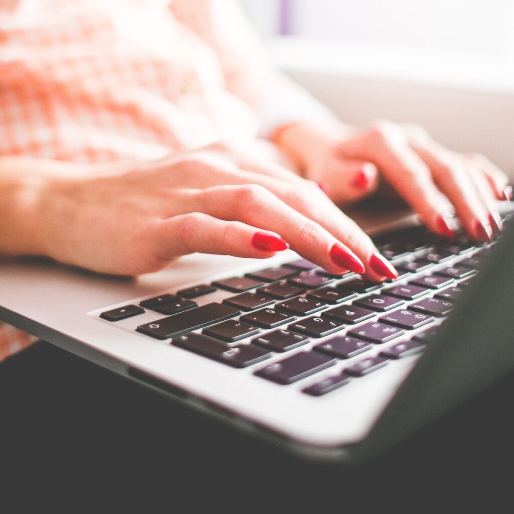 woman with red nails typing on laptop