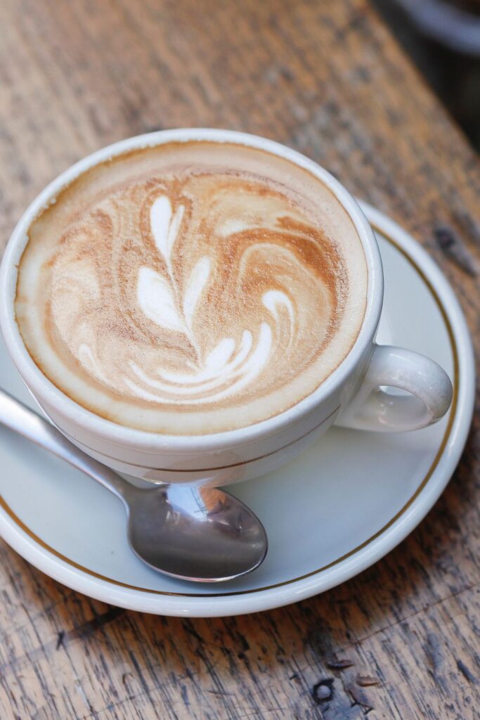 latte art espresso foam milk in white mug on plate with spoon