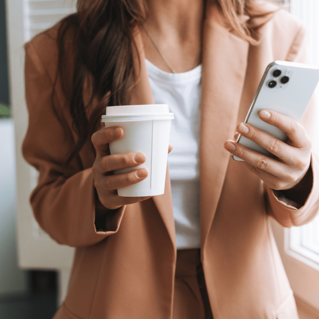 woman holding iphone and coffee